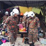 Anggota bomba mengeluarkan jenazah mangsa dari runtuhan rumah pada hari Sabtu.